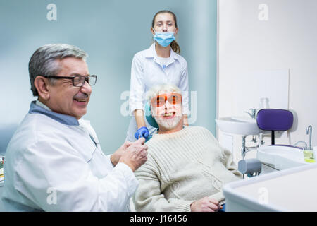 Stomatologist and patient smiling. Elderly male at dentist office. Experienced professionals guarding your health. Stock Photo