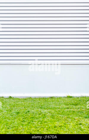 Metallic wall with green grass. Modern urban background Stock Photo