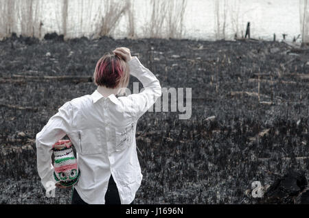 Burned land, girl, white shirt and colorful upside down head Stock Photo