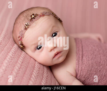 LONDON, UK: Newborn babies look gorgeous showing funny expressions and poses. BRITISH SUMMER babies of 2014 are already bursting with personality from just four-days old. From the sheer joy of being alive to wonder, cheekiness and surprise, these extraordinary pictures show how the next generation have their emotions written all over their faces, even though the tiny people are totally new to the world. Incredibly, while comfortably snoozing the little newborns are capable of sitting in the types of positions even a dedicated yoga master would find eye-wateringly difficult. The woman responsib Stock Photo