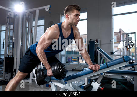 Man doing exercises with one dumbbell in the gym Stock Photo