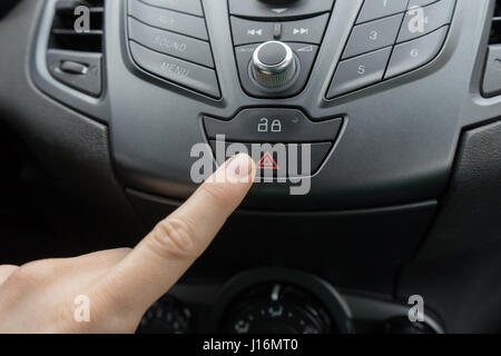 finger pressing car emergency light button Stock Photo