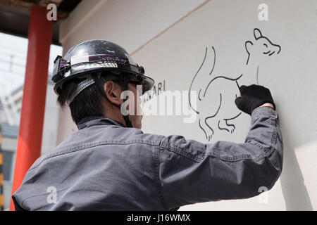 Worker draws a fox on the wall of the train station near Fushimi Inari Shrine, Kyoto, Japan. Foxes are messengers of the gods. Stock Photo