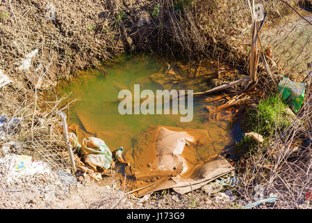 Ronneby, Sweden - March 27, 2017: Documentary of public waste station. Brown, dirty and contaminated water puddle with garbage. Stock Photo