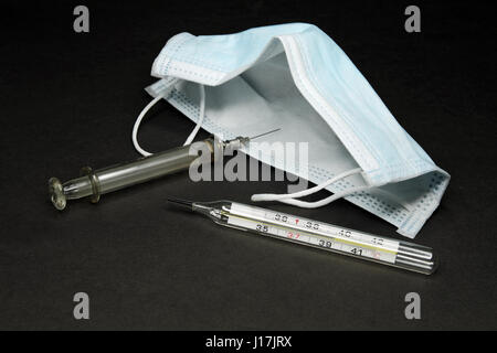 Medical masks, glass syringe and a mercury thermometer (testimony 39,5 C) Stock Photo
