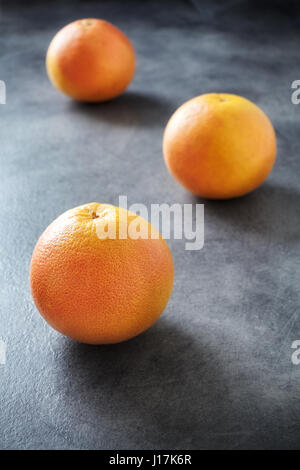 Three whole ripe grapefruits on dark background, selective focus. Stock Photo