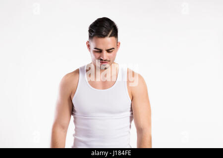 Young fitness man in white sleeveless shirt , studio shot.