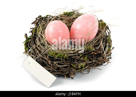 pink easter eggs in a nest with copy space label on white isolated background. Stock Photo