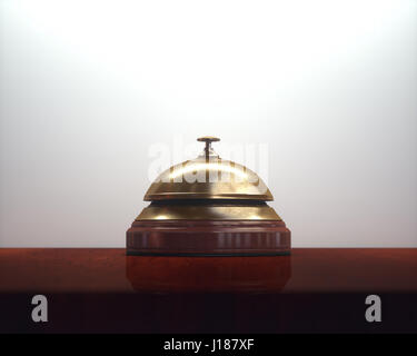 Vintage golden bell on the wooden table of the lobby service. Stock Photo