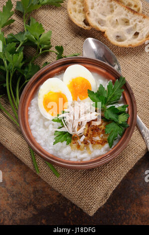 Rice porridge ginger congee with egg, chicken, crispy shallots and parsley Stock Photo