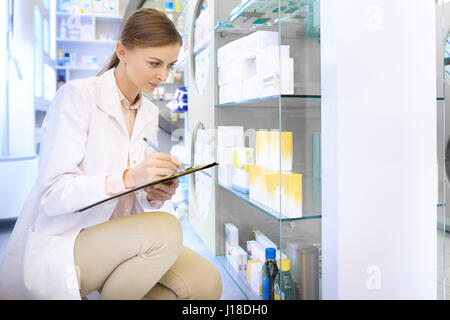 Confident pharmacist doing inventory at drug store Stock Photo