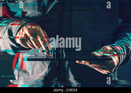 Digital tablet computer in male hands in dark room, glitch effect, low key close up Stock Photo