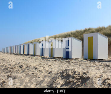 A row of identical beach huts on a sandy beach at Cadzand Bad in Zeeuws-Vlaanderen in the far south west of the Netherlands. Stock Photo