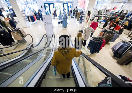 ENSCHEDE, THE NETHERLANDS - APRIL 13, 2017: A woman is going down on the moving staircase in clothes store C&A after it has been reopened. Stock Photo