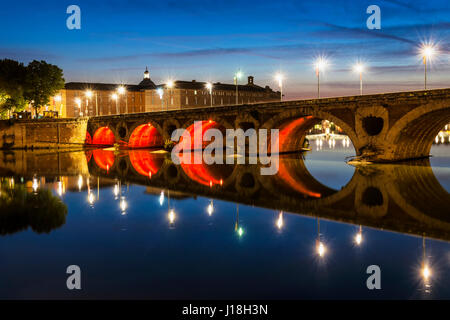 Evening view of historic Pont Neuf in Toulouse, France, with illuminated arches over Garonne River. Stock Photo