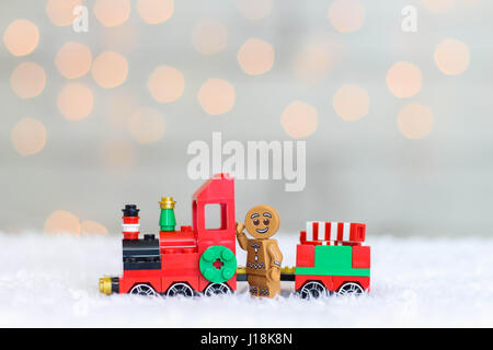 Lego gingerbread man standing in front of a train in the snow with a bokeh background at Christmas Stock Photo