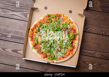 Italian pizza in cardboard box on wooden table. Top view Stock Photo