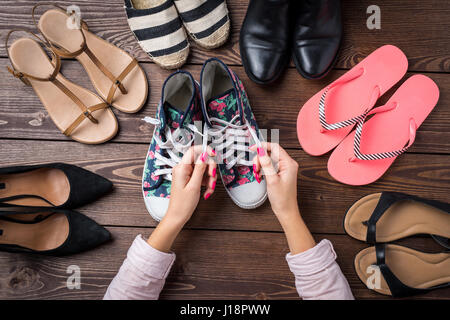 Female shoes collection on wooden table with woman's hands tying shoelace Stock Photo