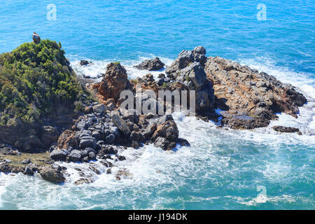Rocks in sea washed by waves during storm shot on sunny day Stock Photo