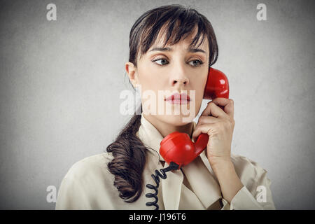 Brunette woman with red retro phone being serious Stock Photo