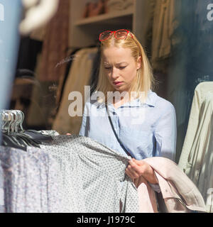 Beautiful woman shopping fashionable clothes in clothing store. Stock Photo