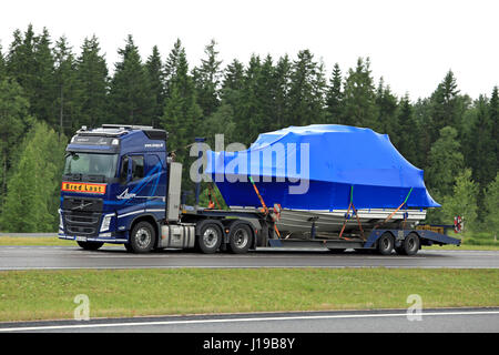 PAIMIO, FINLAND - JUNE 23, 2016: Blue Volvo FH semi truck hauls a boat as exceptional load along freeway. Abnormal transport permit is required, if an Stock Photo