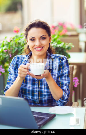Young happy smiling woman woking on computer outdoors Stock Photo