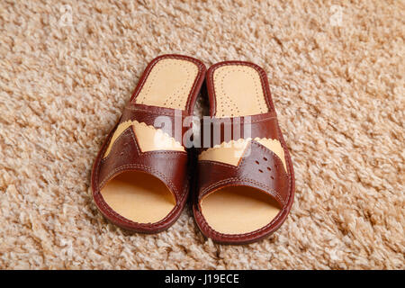 Slippers from leather stand on a fleecy carpet. Focus on the foreground Stock Photo