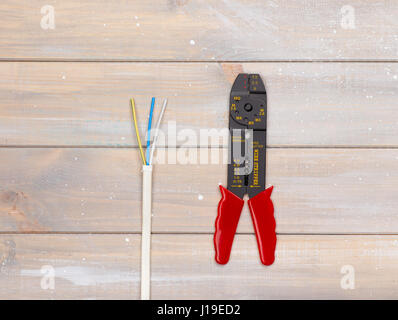 Wire stripper and wires are lying on the wooden background Stock Photo