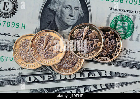 Five £1 coins resting on US dollar bills Stock Photo