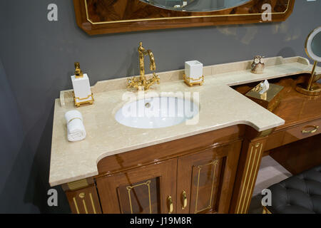 View on luxury bathroom with white inset ceramic washbasin with glossy gold plated metal mixer and accessories Stock Photo