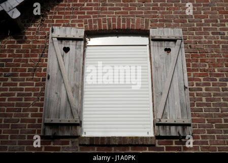 Modern roller shutter in old window with original shutters, Normandy, France Stock Photo