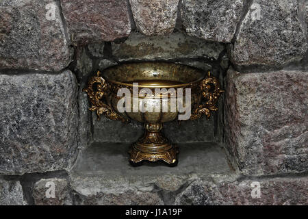 Medieval stone wall of bronze vases on the shelf. Stock Photo