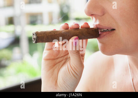Young European woman smokes handmade cigar, closeup photo with selective focus. Dominican Republic Stock Photo