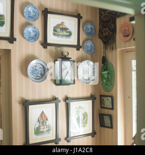 Art and antique tableware hanging on striped wall. Stock Photo