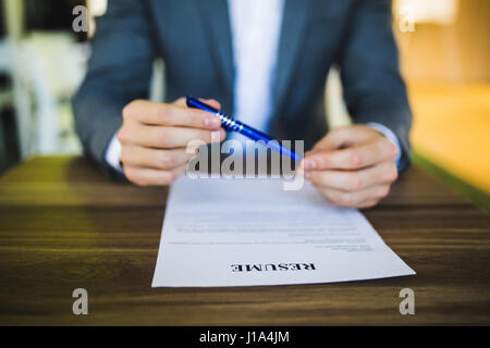 Businessman or job seeker review his resume on his desk before sending to find a new job with pen, notebook, glasses and digital tablet. Stock Photo