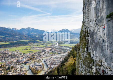 A mountain climber is hanging on the wall of the one of the Barmsteine rock towers with an impressive view over the town Hallein. The Barmsteine are p Stock Photo
