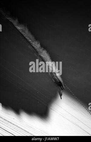 A skier makes a turn on a steep slope in powder snow. Stock Photo