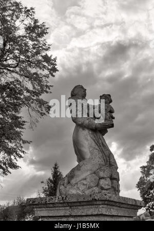 Park statue of St. Joseph baroque Roman Catholic church in black and white against dramatic sky in Pidhirtsi, Ukraine. Pidhirtsi village is located in Stock Photo