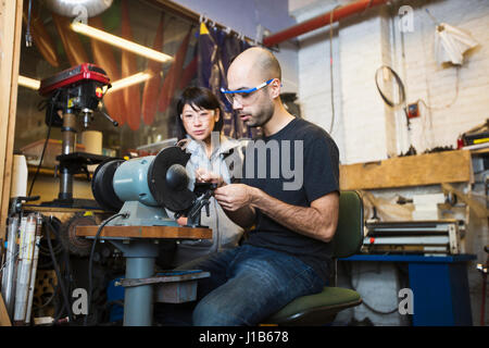 Man and woman using machinery in workshop Stock Photo