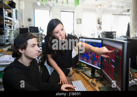 Man and woman examining circuits on computer monitors Stock Photo