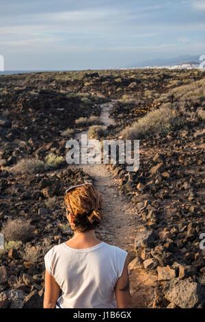 Caucasian woman standing on trail through rocks Stock Photo