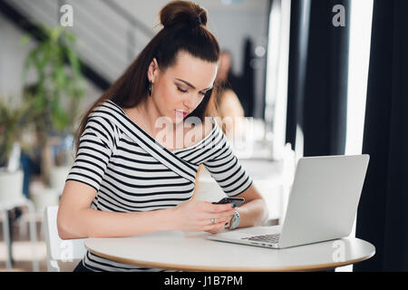 Busy administrative manager of restaurant business chatting on the phone with clients about arrangements and writing all details in notebook. Stock Photo