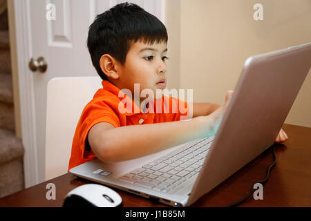 Native American boy sitting at table using laptop Stock Photo