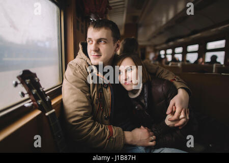 Caucasian couple hugging on train Stock Photo
