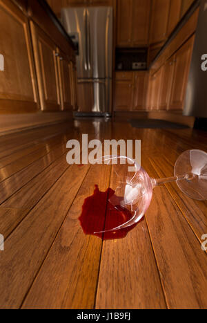 Broken wine glass on floor of modern kitchen - domestic violence concept Stock Photo