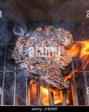 Close up of a BBQ - large piece of beef steak flaming, cooking meat outdoors on a  barbeque Stock Photo