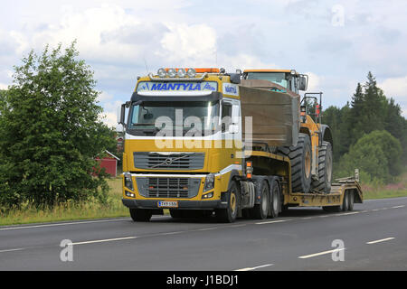 SALO, FINLAND - JULY 30, 2016: Yellow Volvo FH semi of Mantyla E&E transports Caterpillar 980H wheel loader on drop deck trailer on rural highway at s Stock Photo