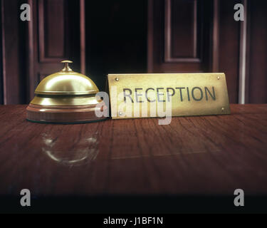 Vintage bell with 'reception' message on the wooden desk of the lobby service. Stock Photo