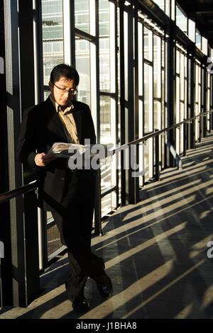 A businessman reading a newspaper in a train station Stock Photo